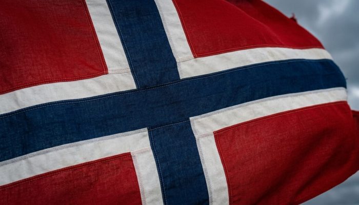 Norway_flag_waving_in_fjord_202607061710-e1783368725654.jpeg