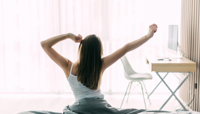 back-view-young-woman-stretching-unmade-bed-after-waking-up-looking-city-view-window.jpg