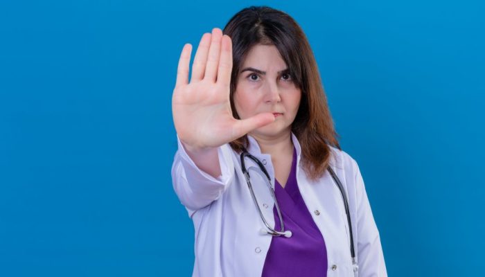 middle-aged-woman-doctor-wearing-white-coat-with-stethoscope-standing-with-open-hand-doing-stop-sign.jpeg