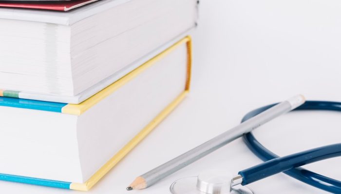 stacked-books-pencil-stethoscope-white-surface-1.jpg