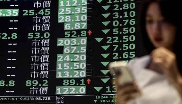 uma-mulher-caminha-em-meio-a-um-quadro-exibindo-precos-medios-de-acoes-na-bolsa-de-valores-de-taiwan.jpeg