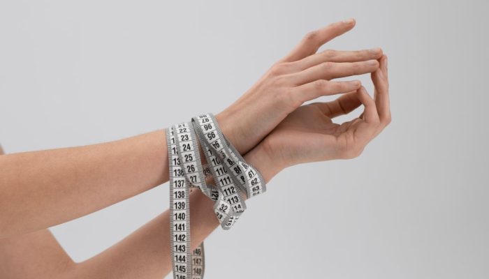 young-woman-with-eating-disorder-using-tape-measure.jpg